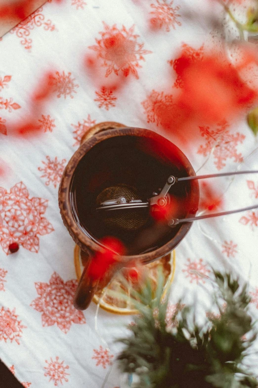 a cup of tea sitting on top of a table, by Julia Pishtar, trending on pexels, folk art, celestial red flowers vibe, winter photograph, red wine, thumbnail