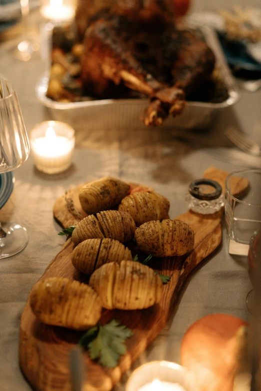 a close up of a plate of food on a table, at a dinner table, potatoes, on a wooden tray, candlelit