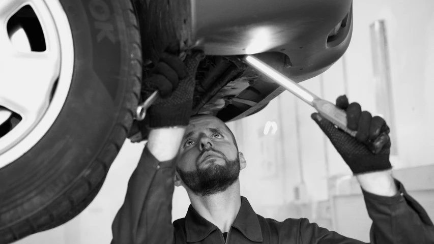 a man working on a tire in a garage, a portrait, pexels, renaissance, bw, pastel', inspect in inventory image, advert