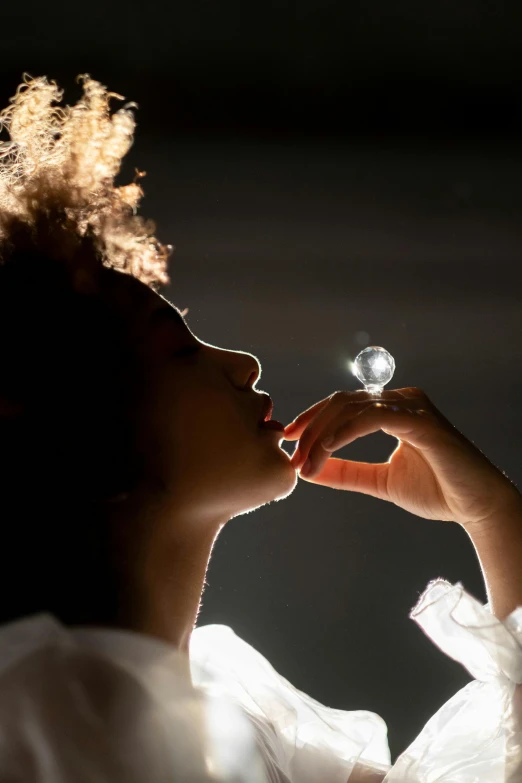 a woman holding a crystal ball in her hand, a hologram, inspired by Carrie Mae Weems, licking out, silver monocle, blowing bubblegum, glass sphere