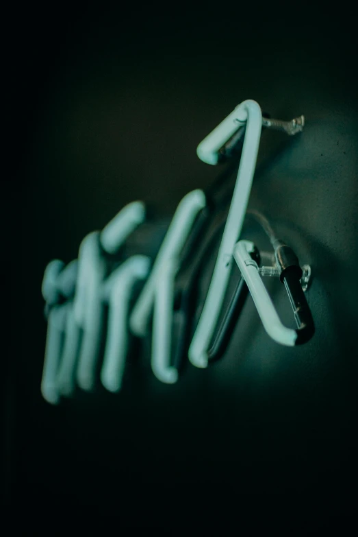a close up of a neon sign on a wall, inspired by Elsa Bleda, unsplash, metal handles, ((greenish blue tones)), laundry hanging, stick figures