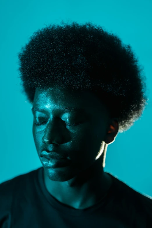 a man with an afro standing in front of a blue background, pexels contest winner, high contrast backlight, black teenage boy, somber turquoise eyes, a photo of a man