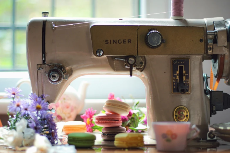 a sewing machine sitting on top of a wooden table, a still life, by Sylvia Wishart, unsplash, macaron, sweets, exterior shot, kitsch