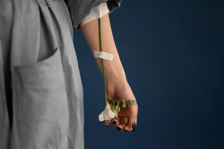 a person holding a flower in their hand, an album cover, inspired by Robert Mapplethorpe, unsplash, surgical iv drip, bandage on arms, intertwined full body view, nika maisuradze