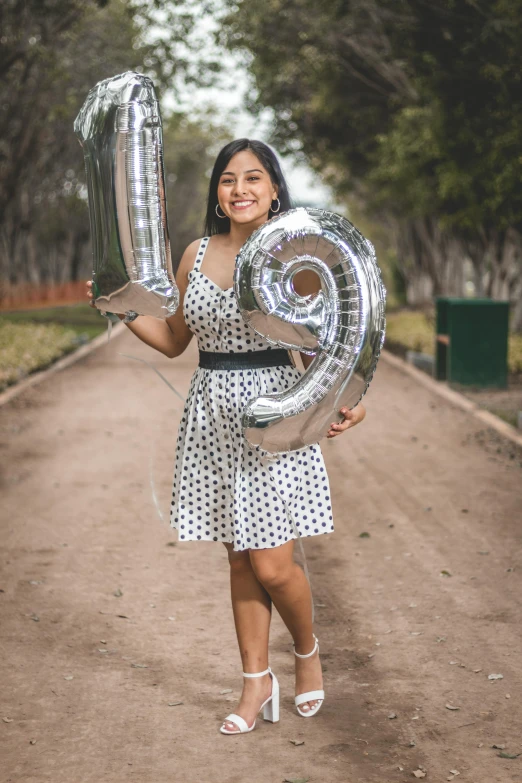 a woman in a polka dot dress holding a silver balloon, by reyna rochin, pexels contest winner, she is mexican, he is about 20 years old | short, 15081959 21121991 01012000 4k, celebrating a birthday