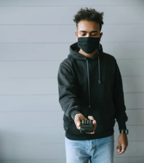 a man in a black hoodie holding a camera, trending on pexels, medical mask, holding controller, avatar image, black man