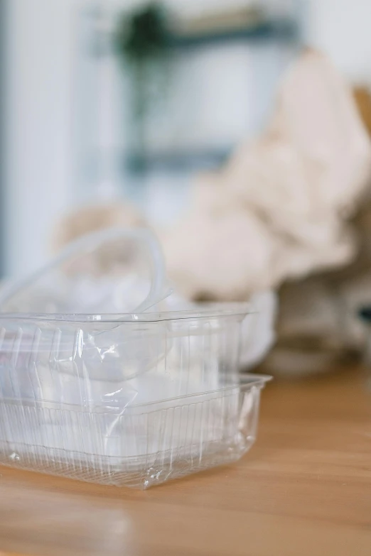 a plastic container sitting on top of a wooden table, unsplash, dressed in plastic bags, organic forms, promo image, detail shot