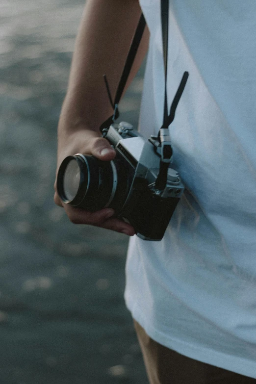 a person holding a camera near a body of water, holding a camera