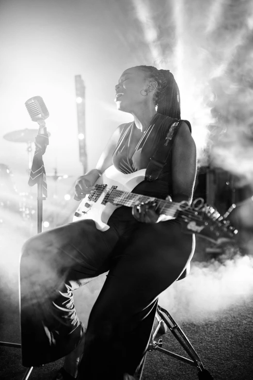 a woman sitting in a chair playing a guitar, in front of smoke behind, photo of a black woman, profile image, flashing lights