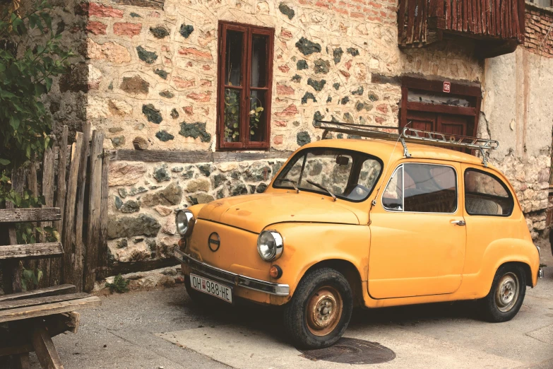 a small yellow car parked in front of a stone building, by Kristian Zahrtmann, pexels contest winner, cyprus, vintage european folk art, square, cheburashka