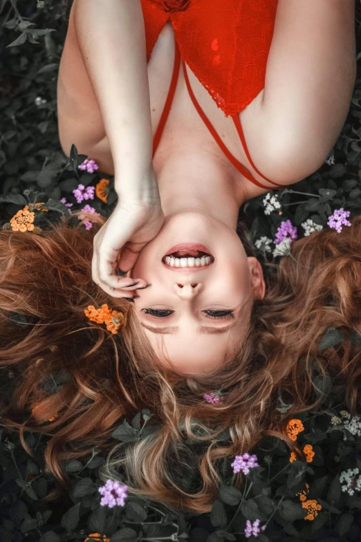 a woman laying on top of a bed of flowers, by irakli nadar, pexels contest winner, flowing ginger hair, open happy mouth, show from below, high angle closeup portrait