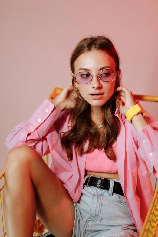 a beautiful young woman sitting on top of a chair, inspired by Elsa Bleda, trending on pexels, pop art, pink glasses, cropped shirt with jacket, portrait sophie mudd, feminine in cute pastel shades