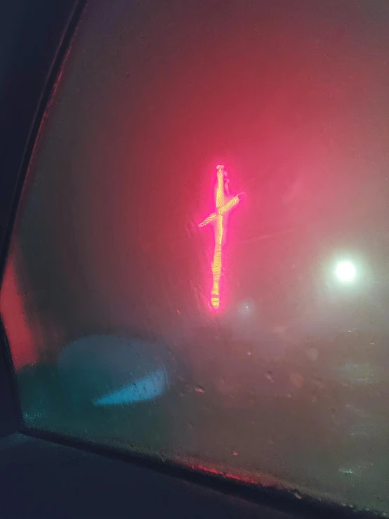 a red traffic light sitting on the side of a road, an album cover, auto-destructive art, neon cross, in the thick fog, # nofilter, inside of a car