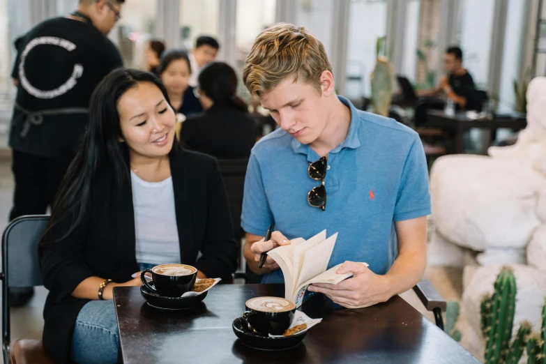 a couple of people that are sitting at a table, holding a book, aussie baristas, ryan jia, profile image