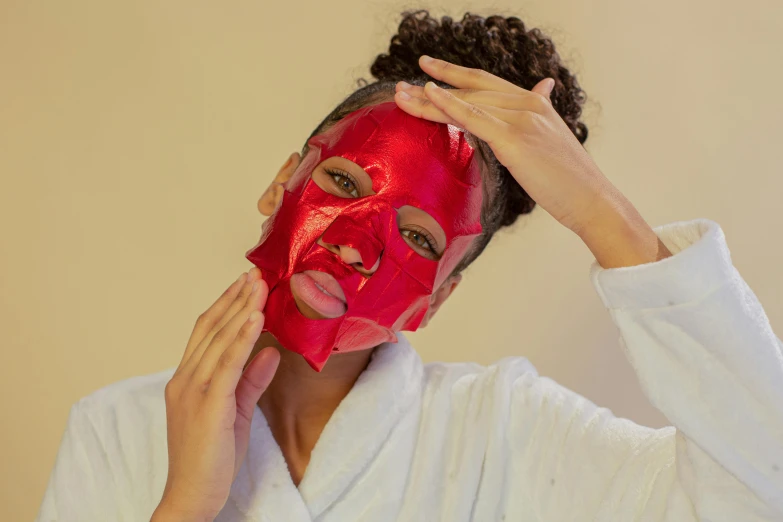 a woman putting a red mask on her face, clear [[bronze]] face [mask], product shot, no skin shown, glowing red