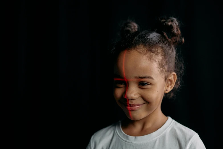 a little girl standing in front of a black background, markings on his face, left eye red stripe, light smile, black young woman