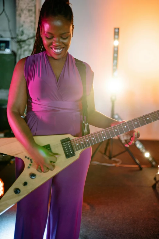 a woman smiles as she plays an electric guitar, inspired by Ray Parker, happening, promo shoot, ( ( dark skin ) ), purple, on fire