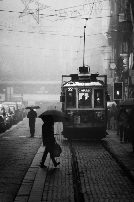 a black and white photo of a trolley on a city street, by Tamas Galambos, tonalism, raining!!!, square, trams, woman