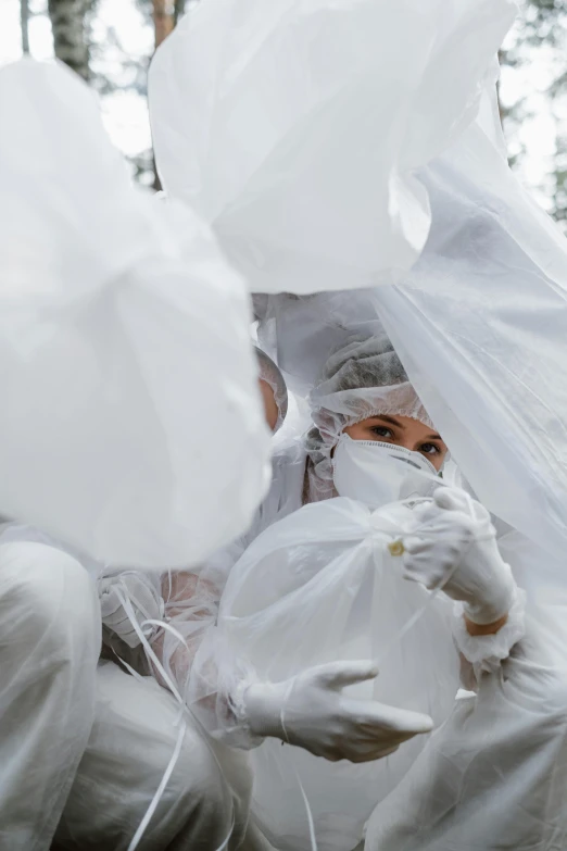 a couple of people sitting on top of a pile of bags, by Liza Donnelly, unsplash, gutai group, wearing translucent veils, white gloves, close-up from above, white mask