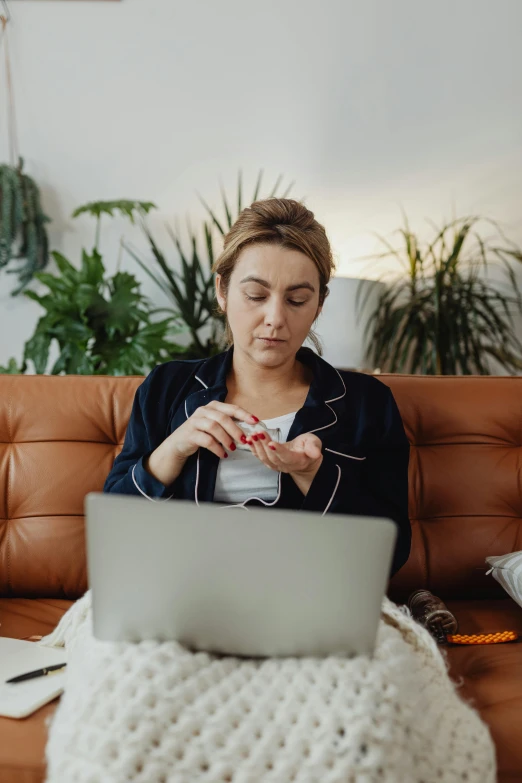 a woman sitting on a couch using a laptop, pexels, happening, holding a syringe, avatar image, serious composure, inspect in inventory image