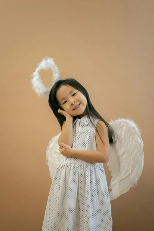 a little girl dressed up as an angel, inspired by Marie Angel, pexels contest winner, young asian girl, plain background, 15081959 21121991 01012000 4k, cupid