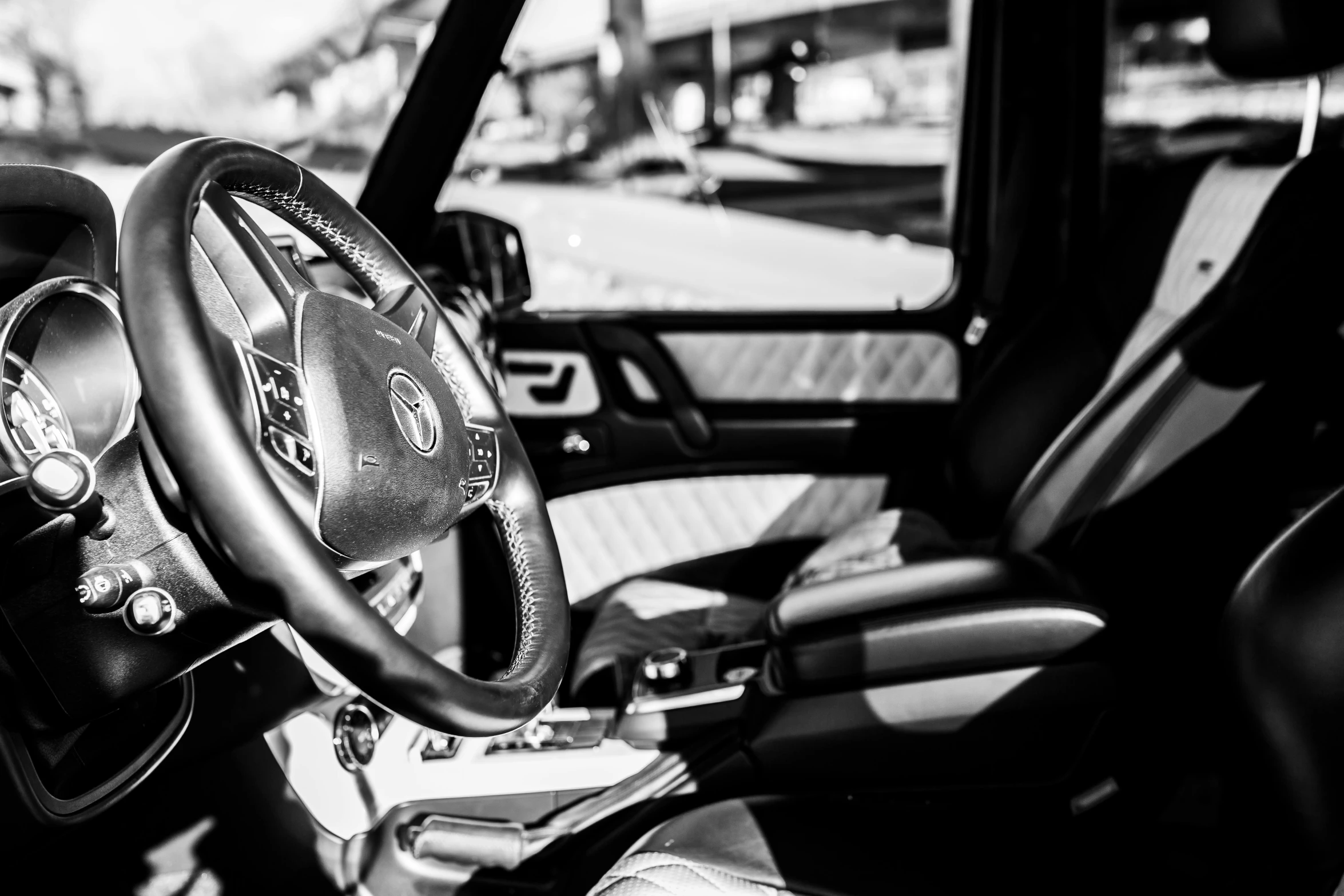 a close up of a steering wheel in a car, a black and white photo, by Daniel Gelon, auto-destructive art, mercedes, intense sunlight, leather interior, very detailed »