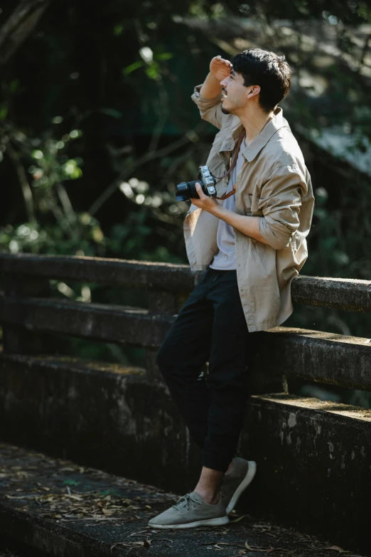 a man sitting on a ledge holding a camera, sitting on a log, unsplash transparent, asian male, jacket