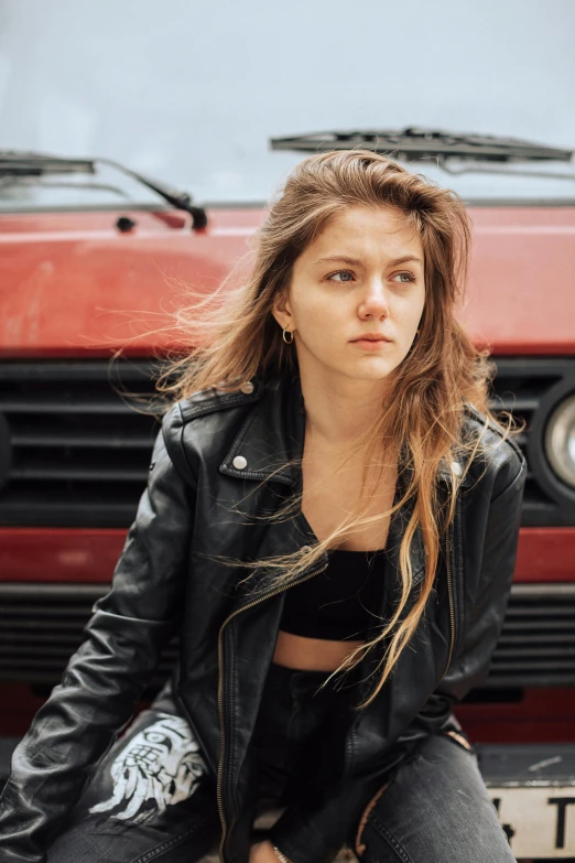 a woman sitting on the hood of a car, an album cover, inspired by Elsa Bleda, trending on unsplash, renaissance, wearing a black leather jacket, good looking face, ukrainian girl, square