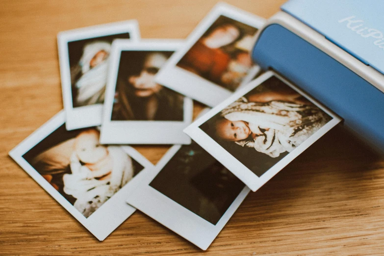 a polaroid camera sitting on top of a wooden table, a polaroid photo, by Julia Pishtar, trending on pexels, contact sheet, family photo, coloured polaroid photograph, small portraits