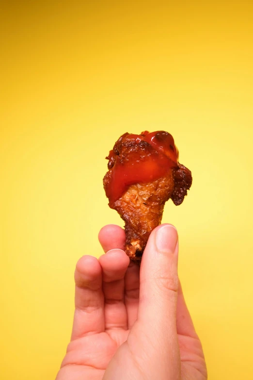 a person holding a piece of food in their hand, by Jessie Algie, unsplash, photorealism, fiery wings, glazed, minn, meaty