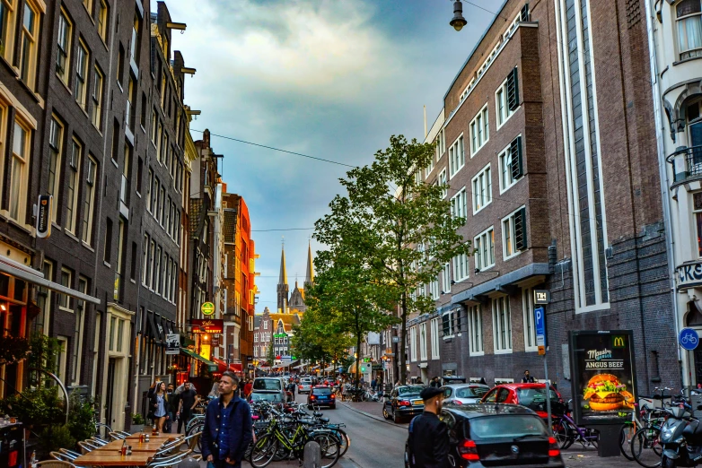 a group of people walking down a street next to tall buildings, a photo, by Jan Tengnagel, pexels contest winner, happening, view of houses in amsterdam, late summer evening, square, a colorful