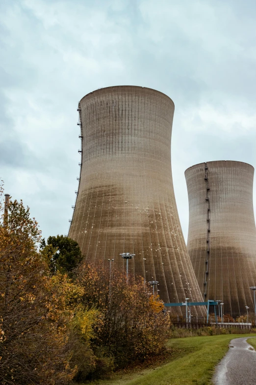 a couple of cooling towers sitting on top of a lush green field, unsplash, nuclear art, 2022 photograph, alabama, nuclear winter, multiple stories