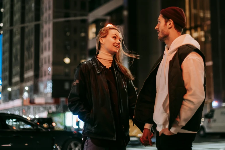 a man and woman standing on a city street at night, trending on pexels, sydney sweeney, flirting smiling, profile image, leather clothing