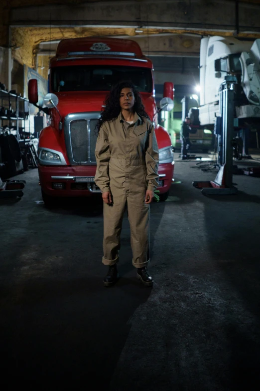 a woman standing in front of a semi truck, renaissance, wearing dirty flight suit, in a workshop, promo still, halloween