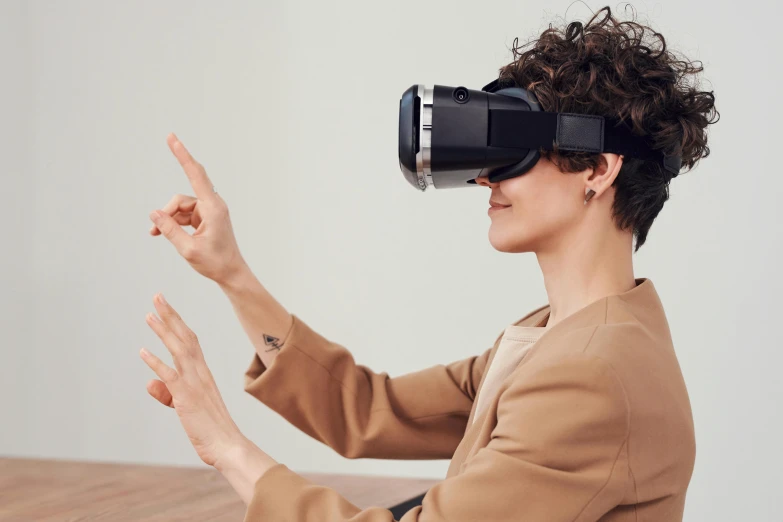 a woman sitting at a table wearing a virtual reality headset, trending on pexels, triumphant pose, mit technology review, high angle shot, hiperrealista