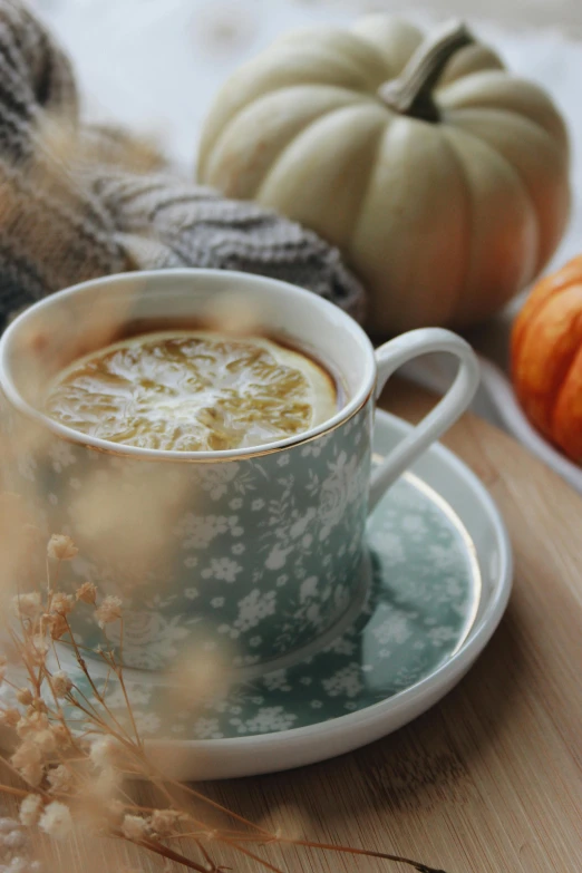 a cup of coffee sitting on top of a saucer, pumpkins, in muted colours, lemon, soup