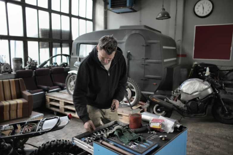 a man working on a motorcycle in a garage, pexels contest winner, arbeitsrat für kunst, radio equipment, avatar image, balding older cyborg repairing, cars and people