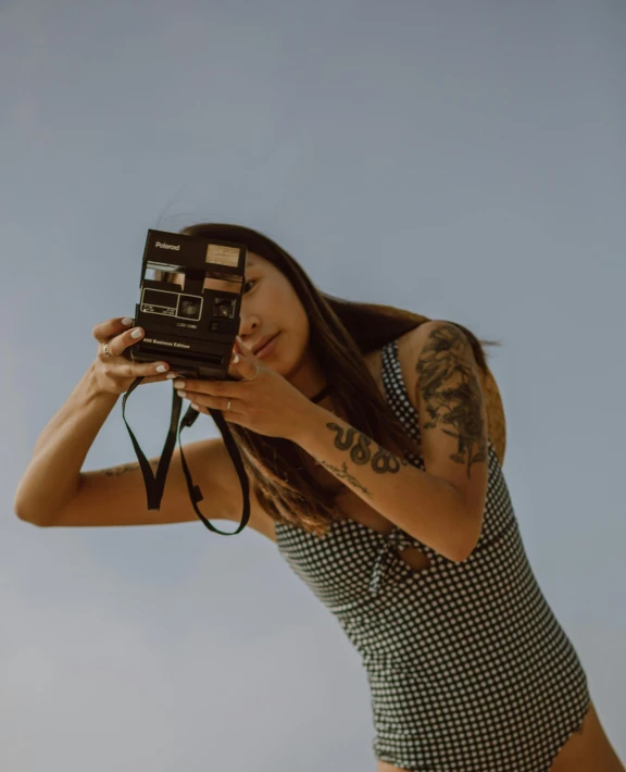 a woman taking a picture with a camera, a polaroid photo, inspired by Elsa Bleda, realism, tattooed, unsplash transparent, album cover, looking to the sky