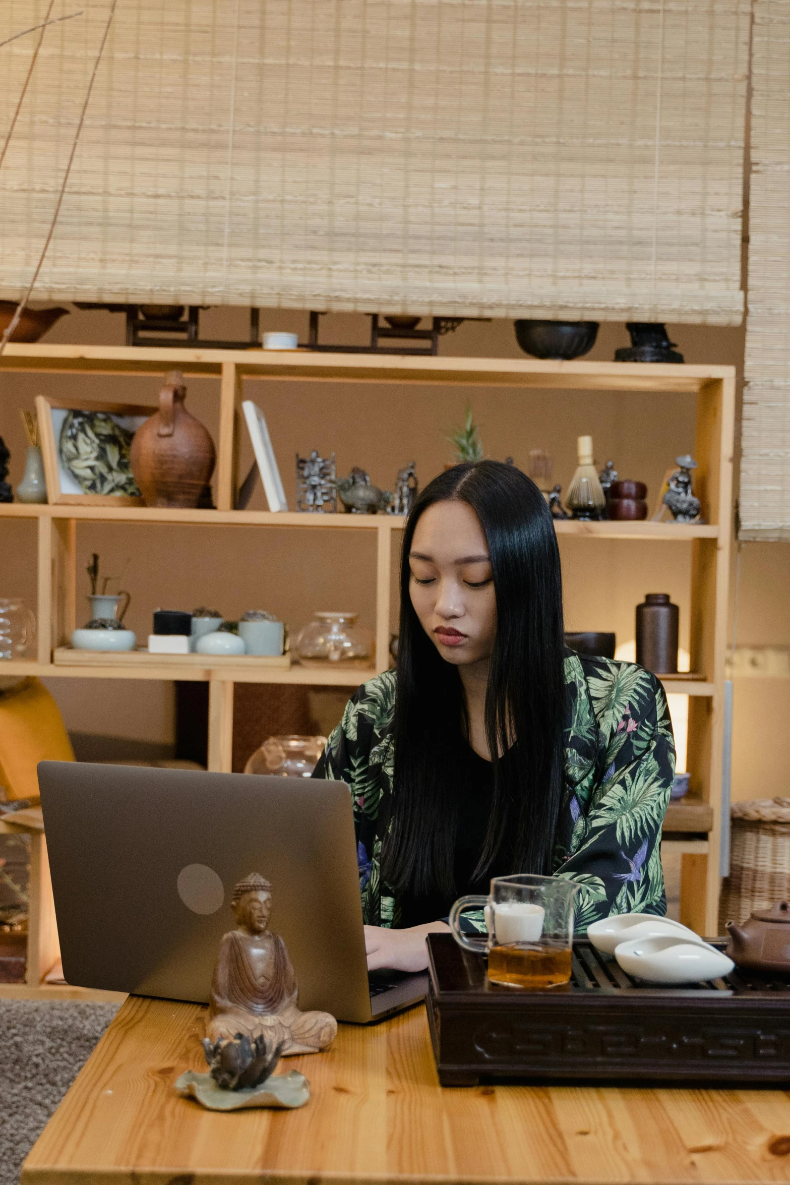 a woman sitting at a table with a laptop, inspired by Li Di, unsplash, ukiyo-e, medium shot angle, brown, asian human, staff