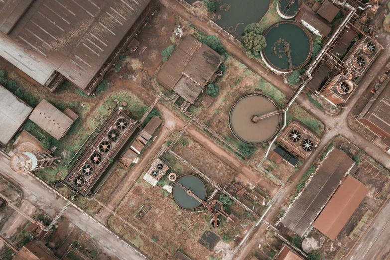 an aerial view of a large industrial area, a colorized photo, by Adam Marczyński, pexels contest winner, renaissance, brown water, sewer background, black, abandoned laboratory