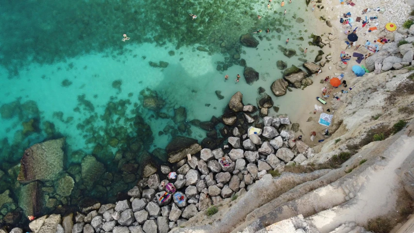 a group of people standing on top of a beach next to a body of water, pexels contest winner, renaissance, looking down from above, costa blanca, crystal clear water, thumbnail