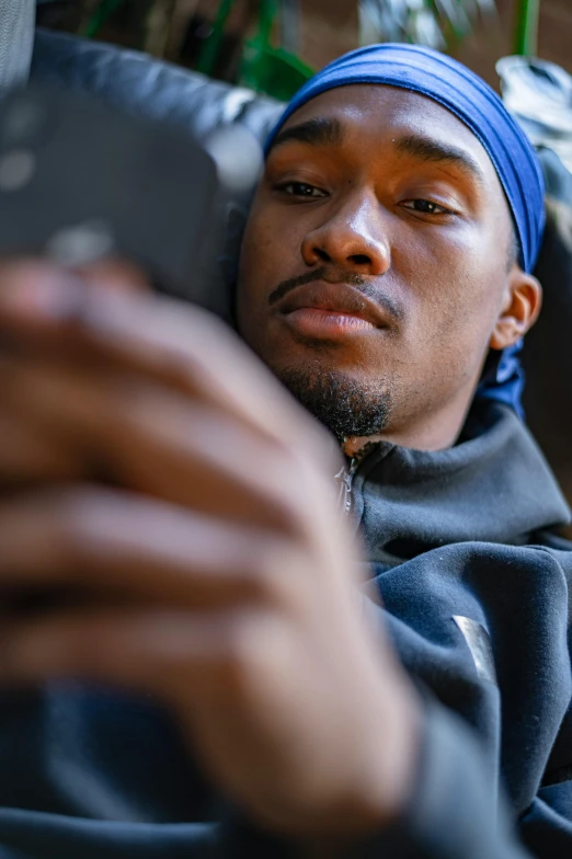 a close up of a person holding a cell phone, by Niko Henrichon, wearing a blue hoodie, black man, relaxing, avatar image