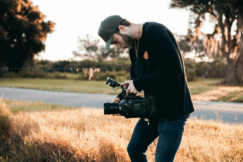 a man that is standing in the grass with a camera, pexels contest winner, video art, screenwriter, professional shooting, cinematic ligting, production ig