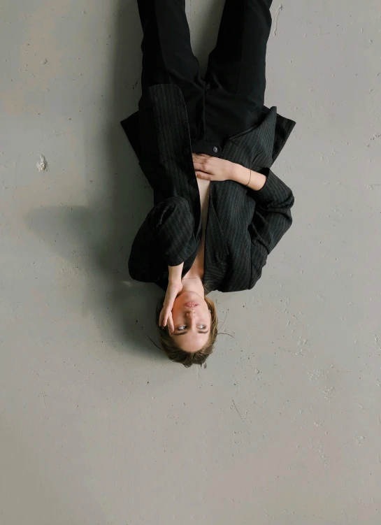 a man is upside down on the floor, by Nina Hamnett, trending on unsplash, visual art, girl in a suit, portrait androgynous girl, on a pale background, black in