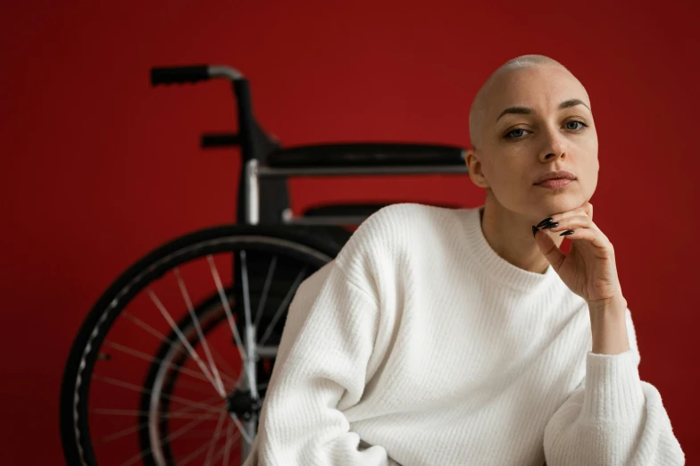 a woman sitting in front of a wheel chair, a portrait, pexels contest winner, antipodeans, no hair completely bald, bicycle, wearing a tracksuit, charli bowater and artgeem