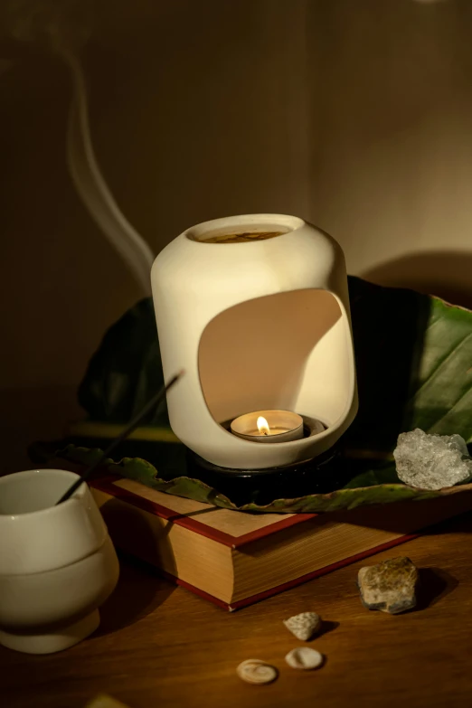 a lit candle sitting on top of a wooden table, a still life, inspired by Kanō Mitsunobu, renaissance, white sweeping arches, healing pods, made of glowing wax and ceramic, pot