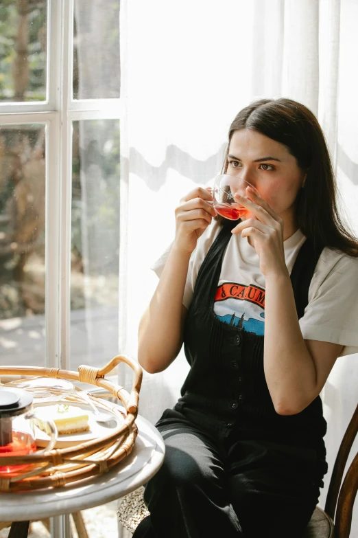 a woman sitting at a table eating a slice of pizza, secret tea society, drinking cough syrup, black shirt with red suspenders, rex orange county