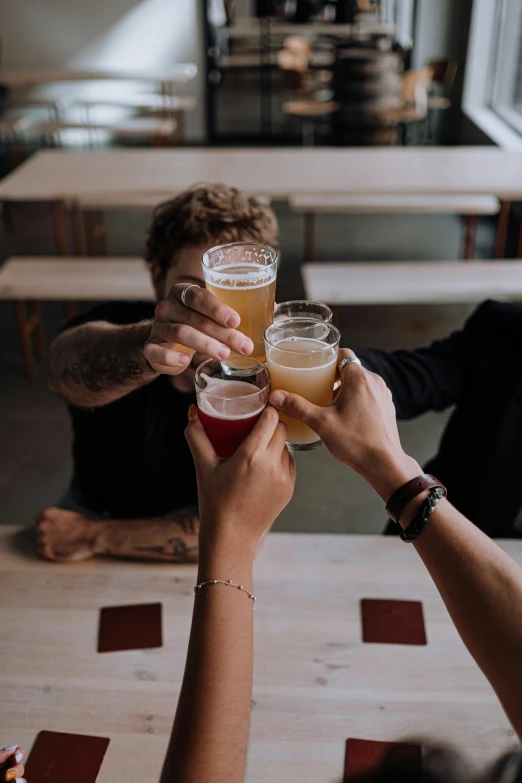 a group of people clinking glasses of beer, by Carey Morris, pexels contest winner, but minimalist, sitting on a table, instagram story, wings spread