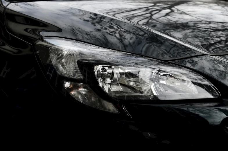 a close up of the headlights of a black car, by Tom Bonson, pexels contest winner, reflective material, black and silver, full view of a car, glass and metal : : peugot onyx