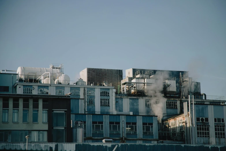 a building with a lot of smoke coming out of it, inspired by Elsa Bleda, unsplash contest winner, smelters, exterior view, toothpaste refinery, low quality photo